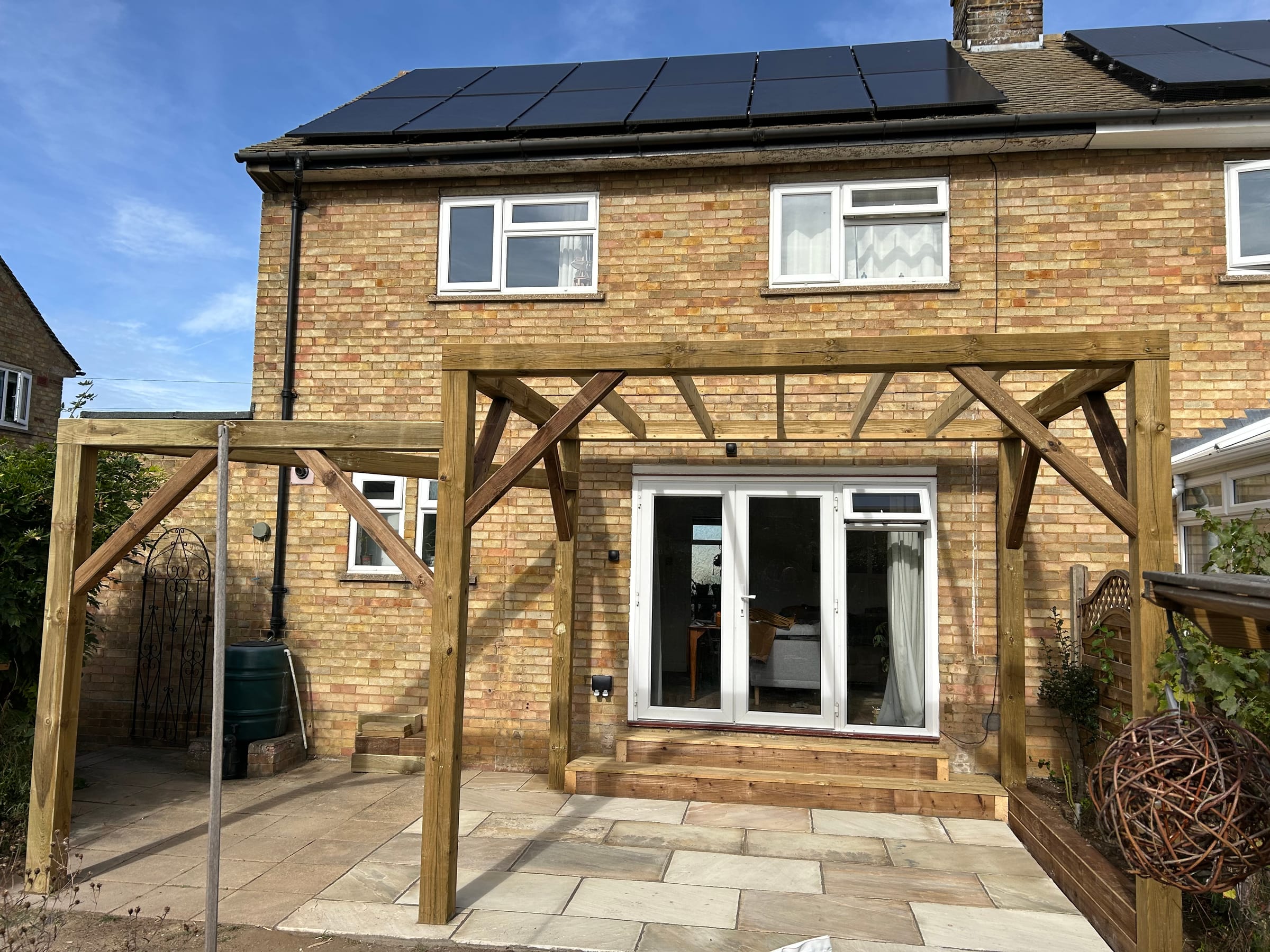 A new timber pergola frame over the patio at the back of a house