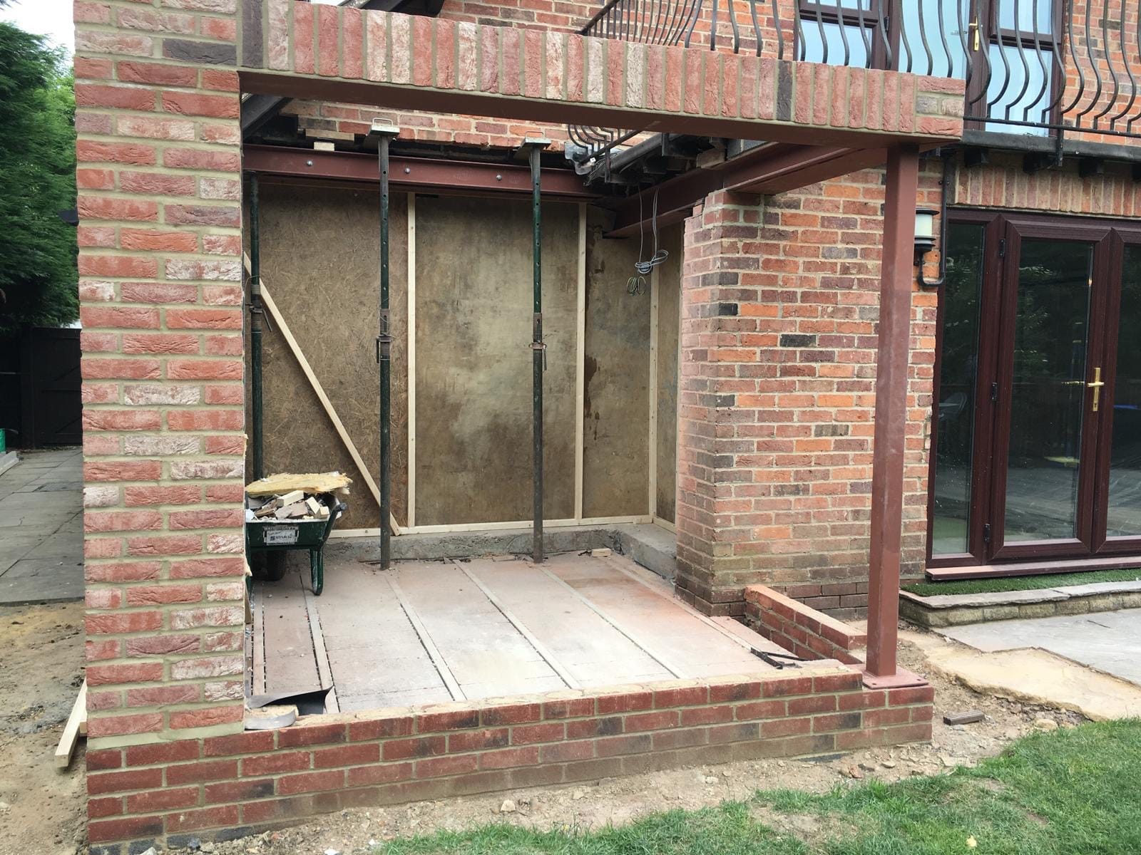 A wide corner opening in a new brick extension, held up by steel posts