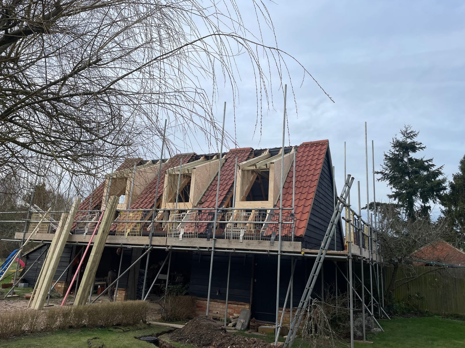 A weatherboarded building under construction, with dormers framed in the roof