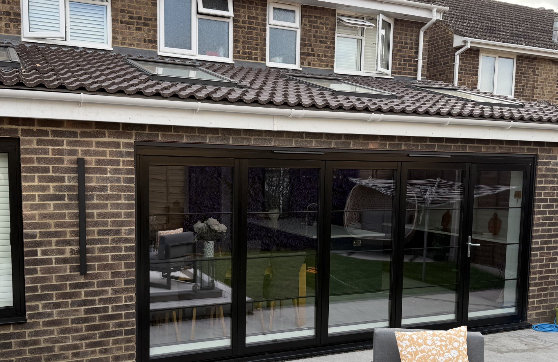 A single storey rear extension with black bi-fold doors and roof windows in the tiled roof