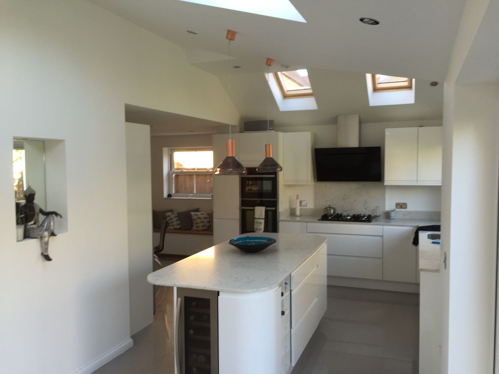 A kitchen extension with a white island under roof windows