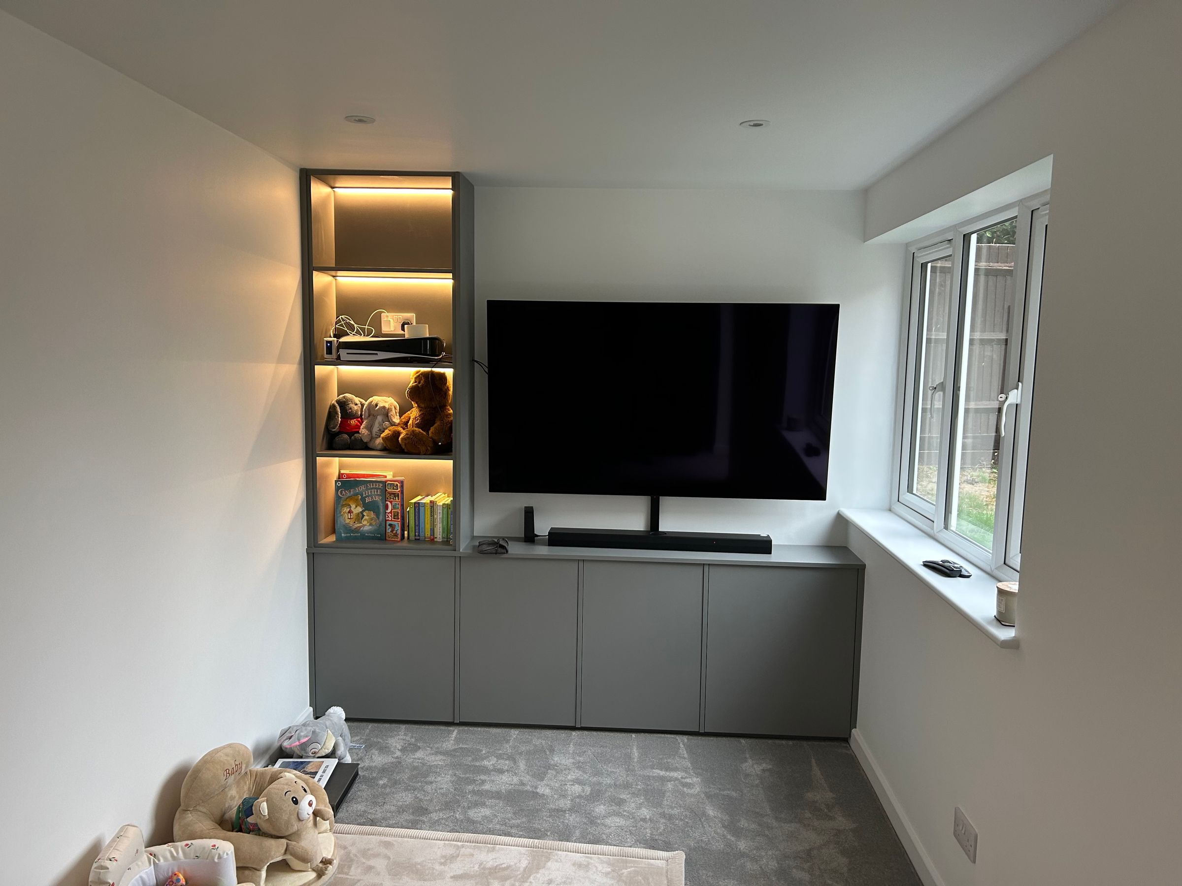 A garage converted into a snug with a fitted media wall and shelving