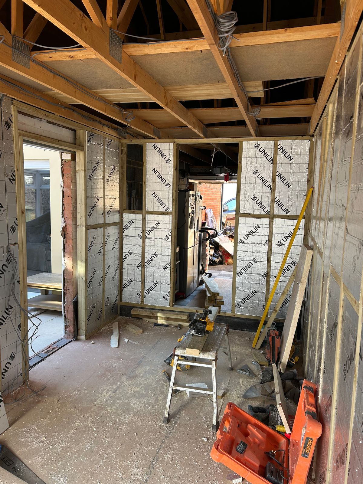 A garage stripped back to its roof timbers, with insulation going into the walls