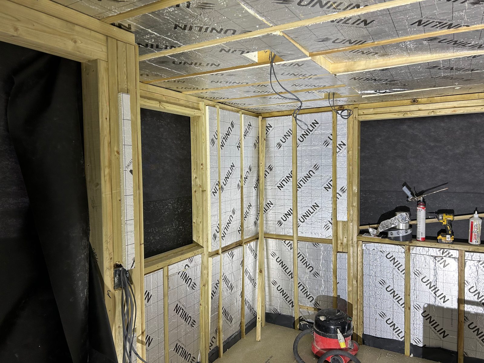 A garden room's timber frame with insulation boards fitted between the studs