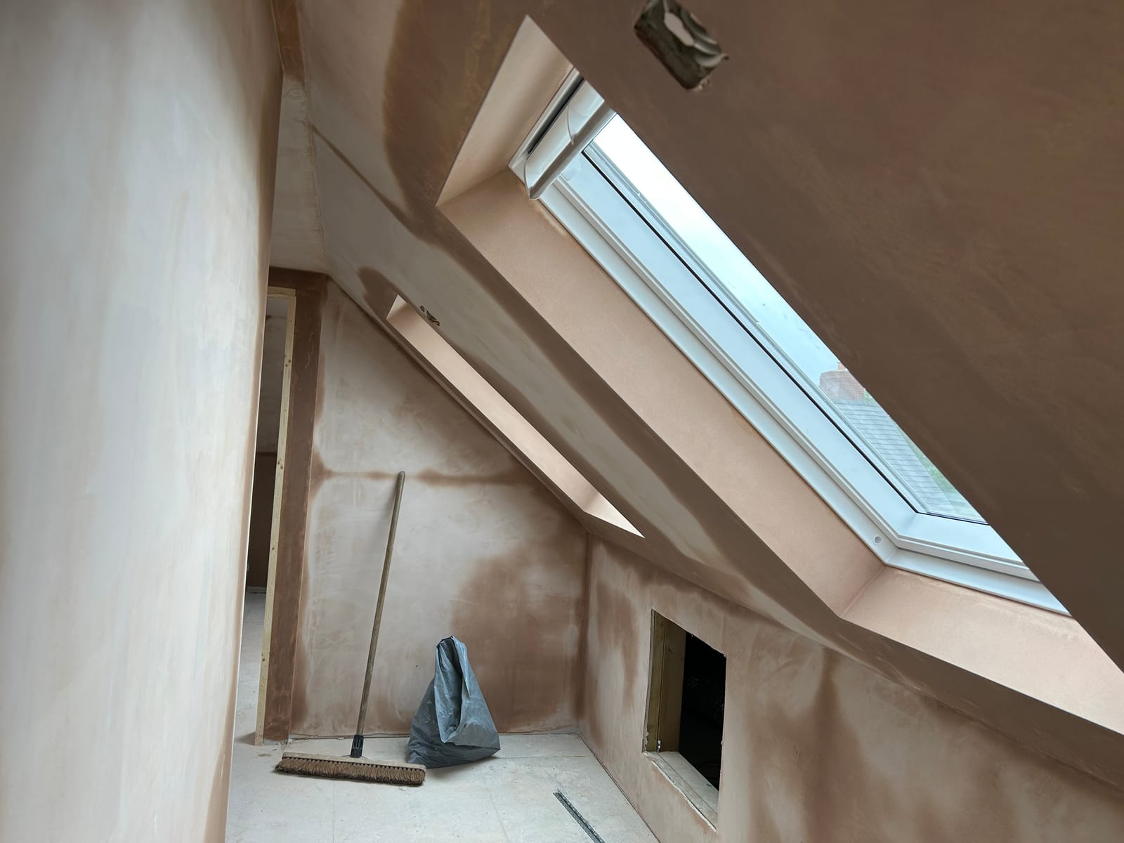 A freshly plastered loft room with a roof window