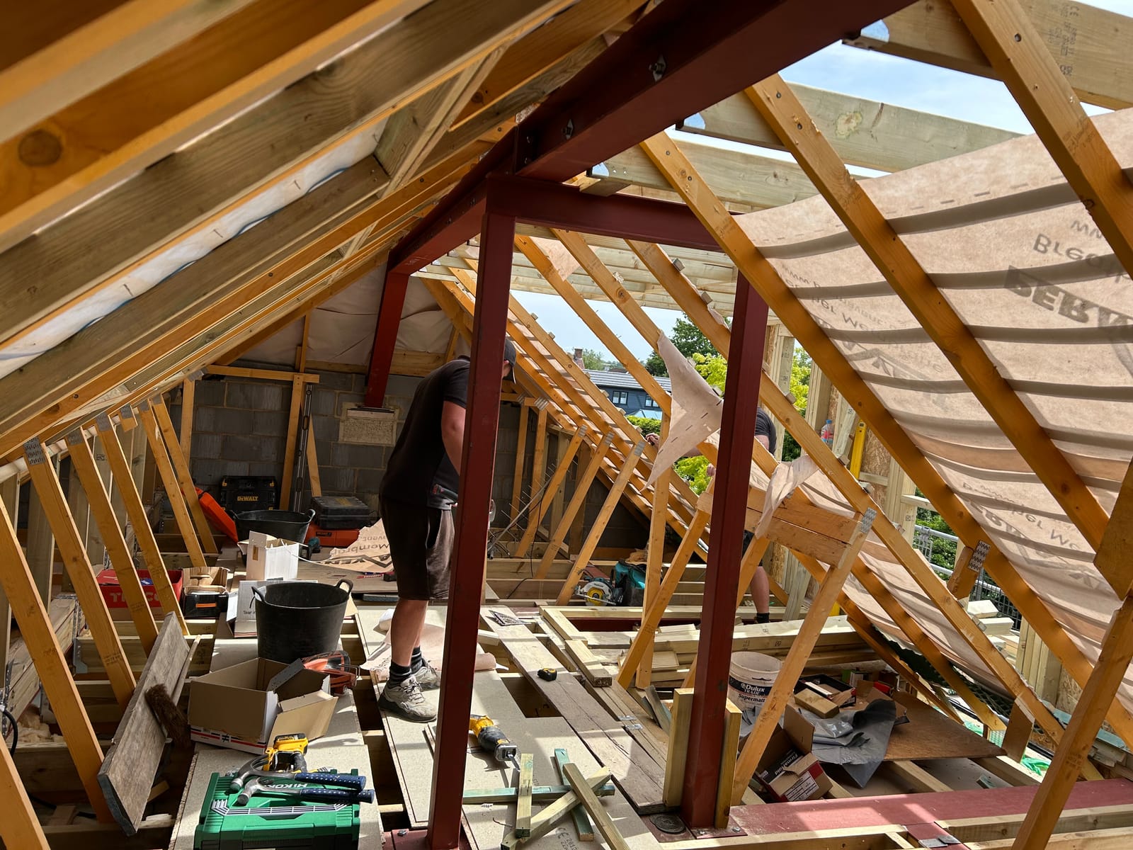 A builder working among new steels and roof timbers in a loft
