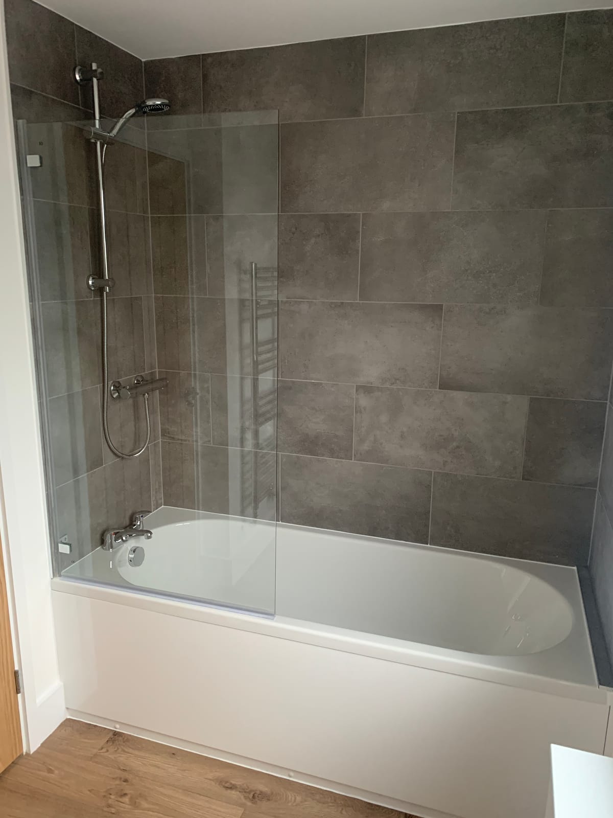 A refitted bathroom with a tiled shower over the bath