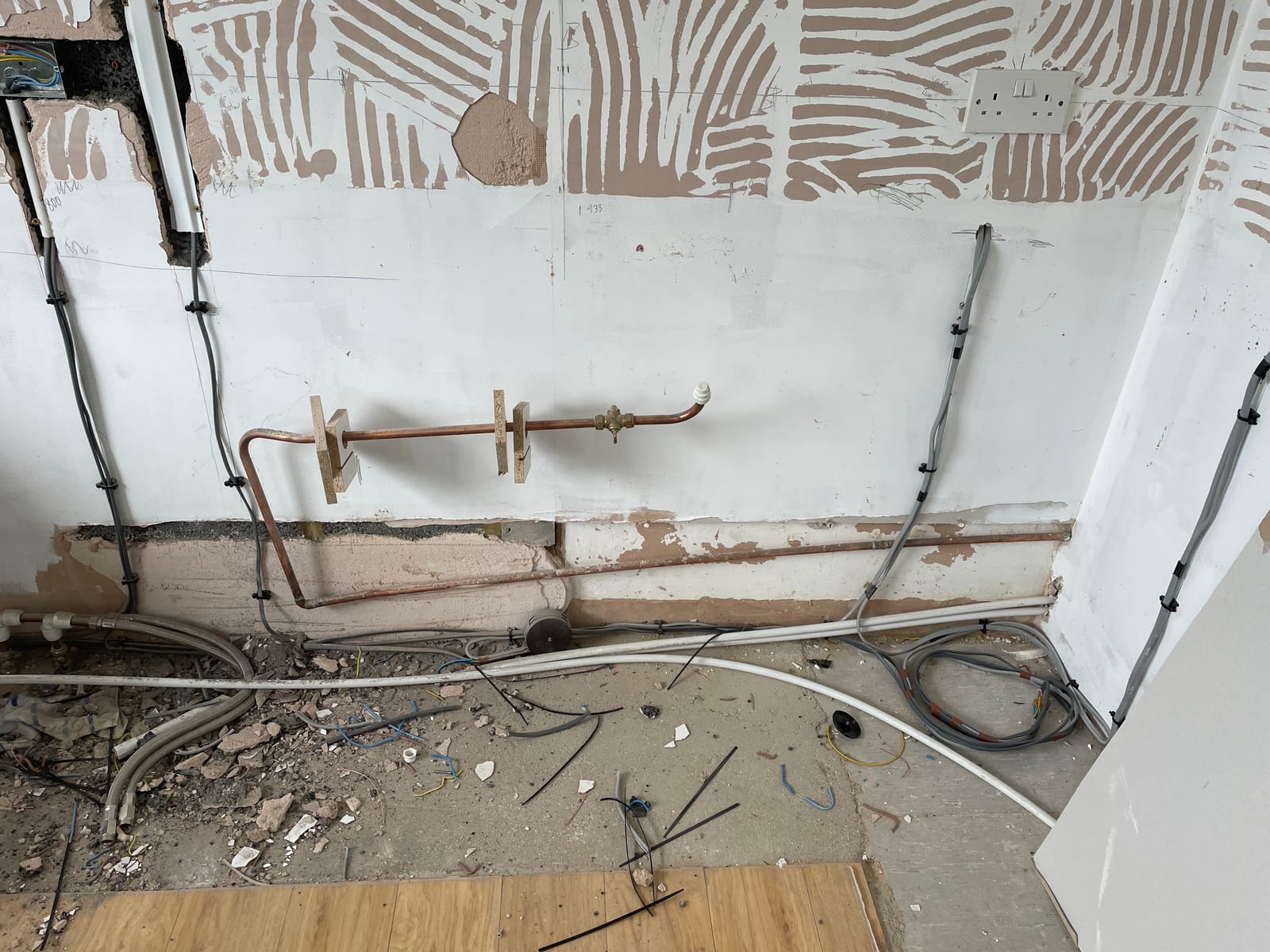 A stripped back wall with new pipework and cabling run in