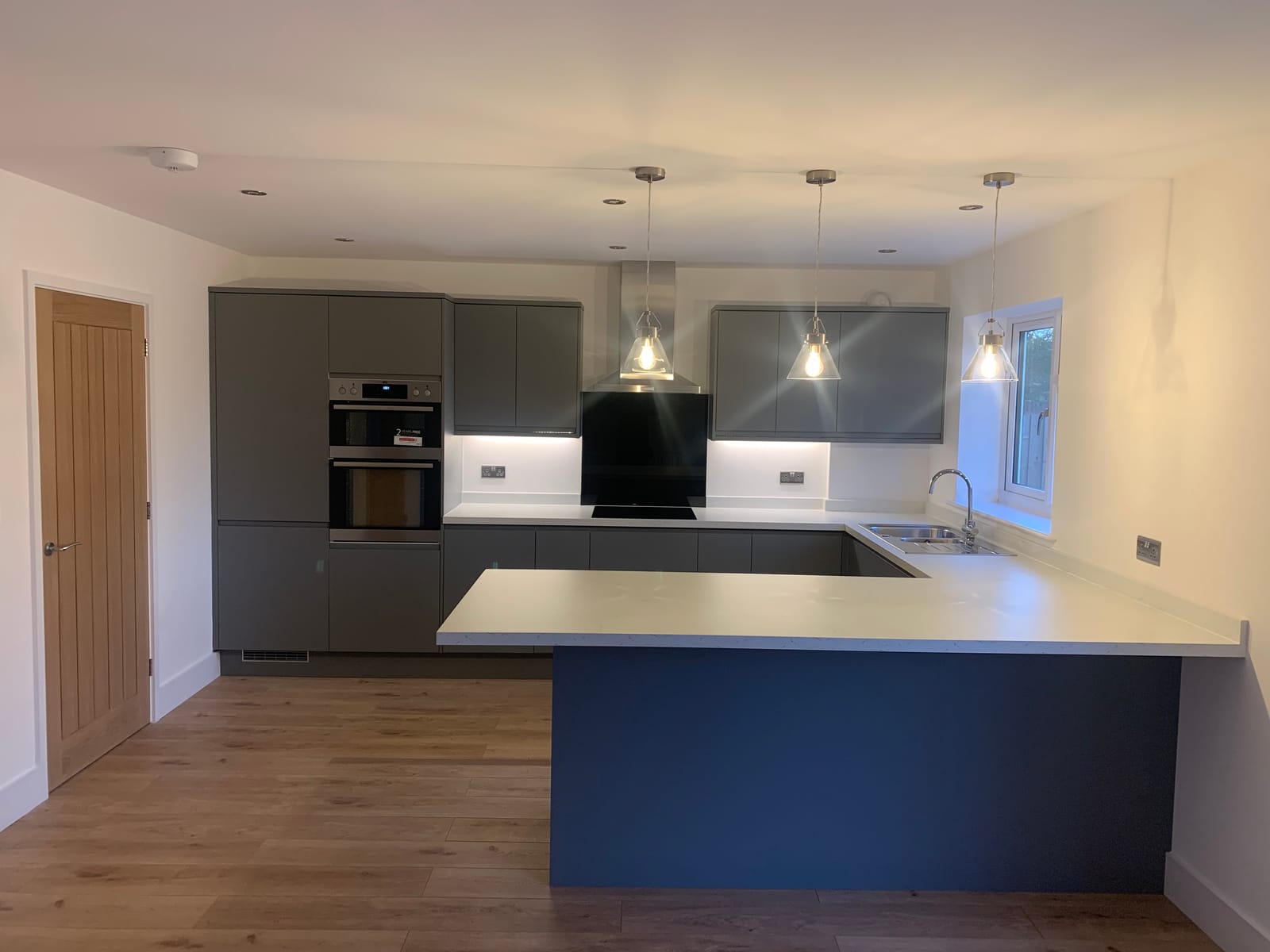 A new kitchen with grey units and a navy breakfast bar
